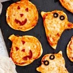 Mini halloween pizzas shaped like ghosts and jack-o-lanterns served up on a slate board.