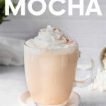 Cinnamon sprinkles down over the whipped cream garnish on a white chocolate mocha. A text overlay reads, "White Chocolate Mocha."