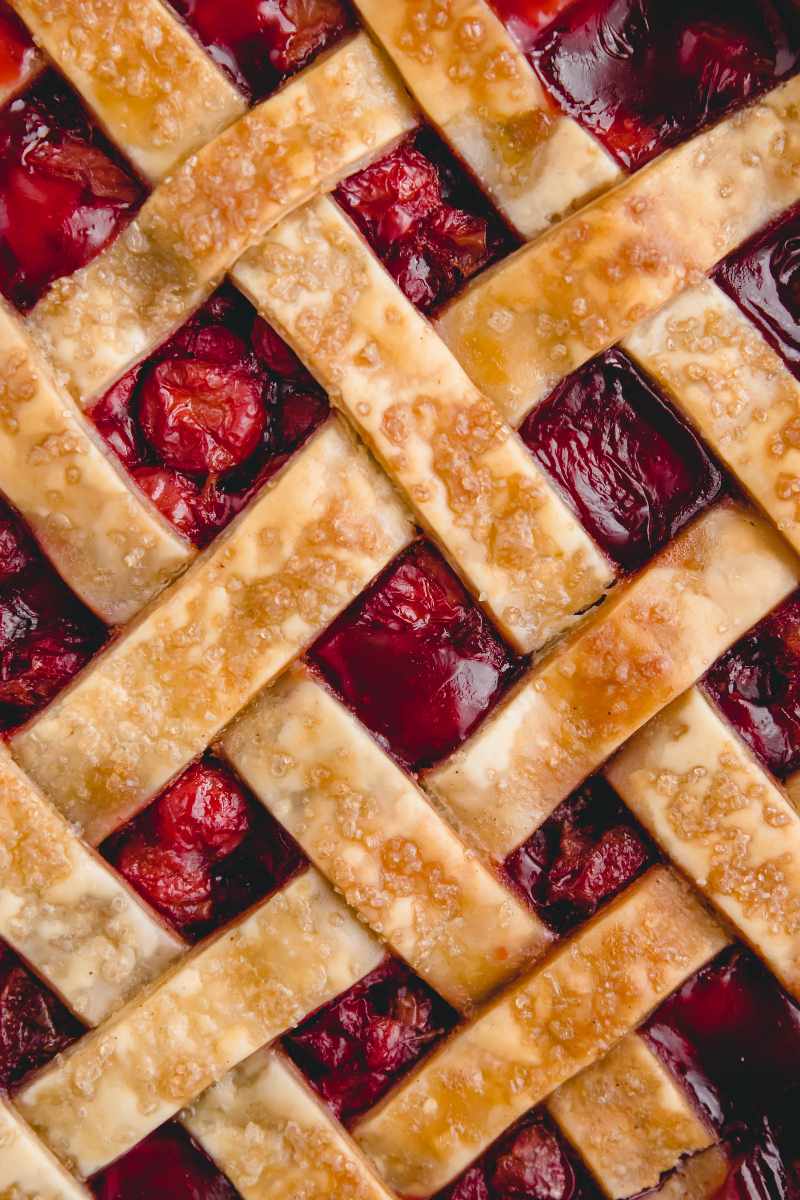 Close view of a lattice topped pie with a deep red cherry filling.