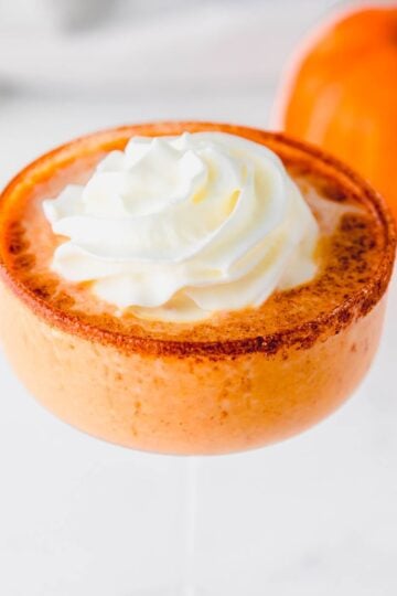 Whipped cream and cinnamon garnish on top of a pumpkin martini