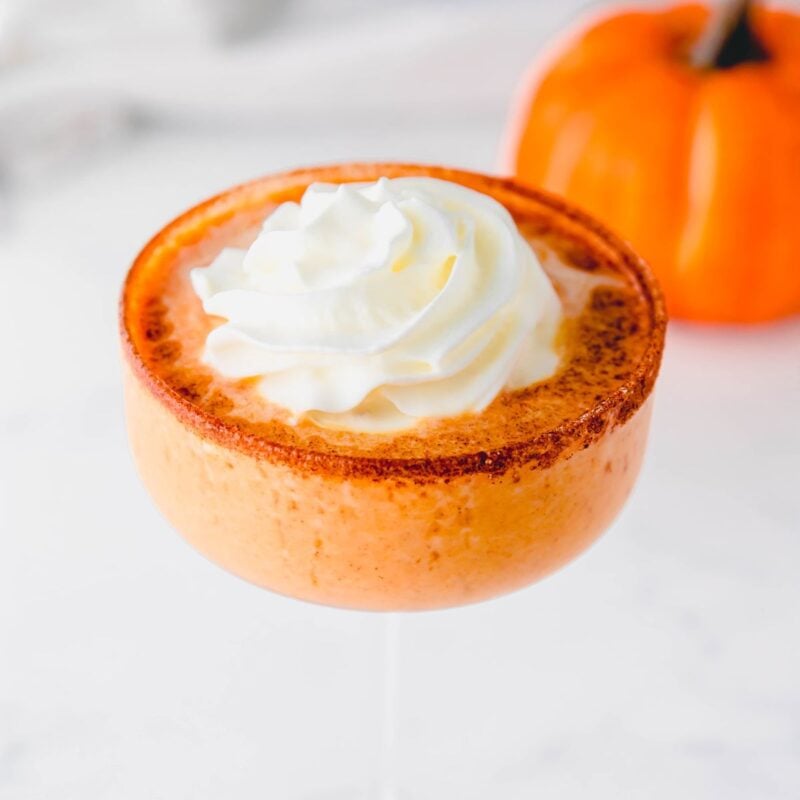 Whipped cream and cinnamon garnish on top of a pumpkin martini