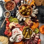A spooky Halloween themed charcuterie board on a black slate tray sits on a gray countertop.