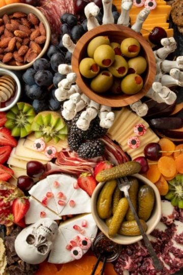 A spooky Halloween themed charcuterie board on a black slate tray sits on a gray countertop.