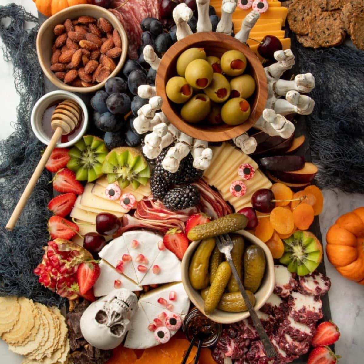 A spooky Halloween themed charcuterie board on a black slate tray sits on a gray countertop.