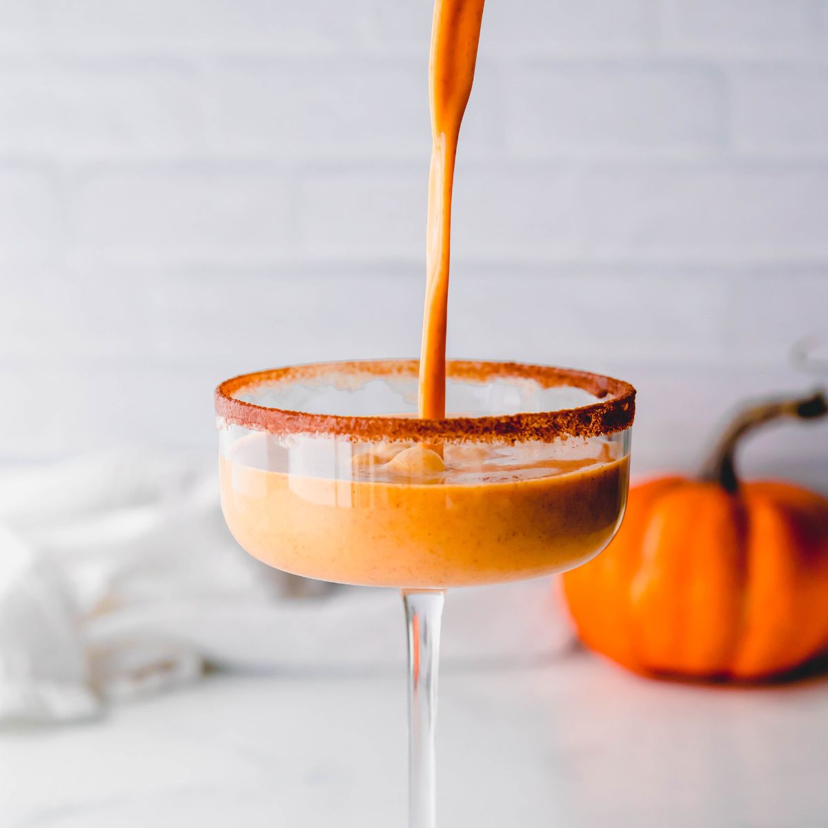 Pouring a pumpkin pie martini into a martini glass