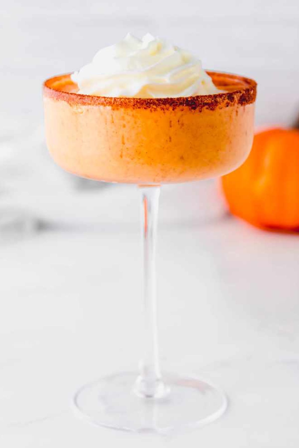 A pumpkin pie martini in a glass sits on a white marble countertop