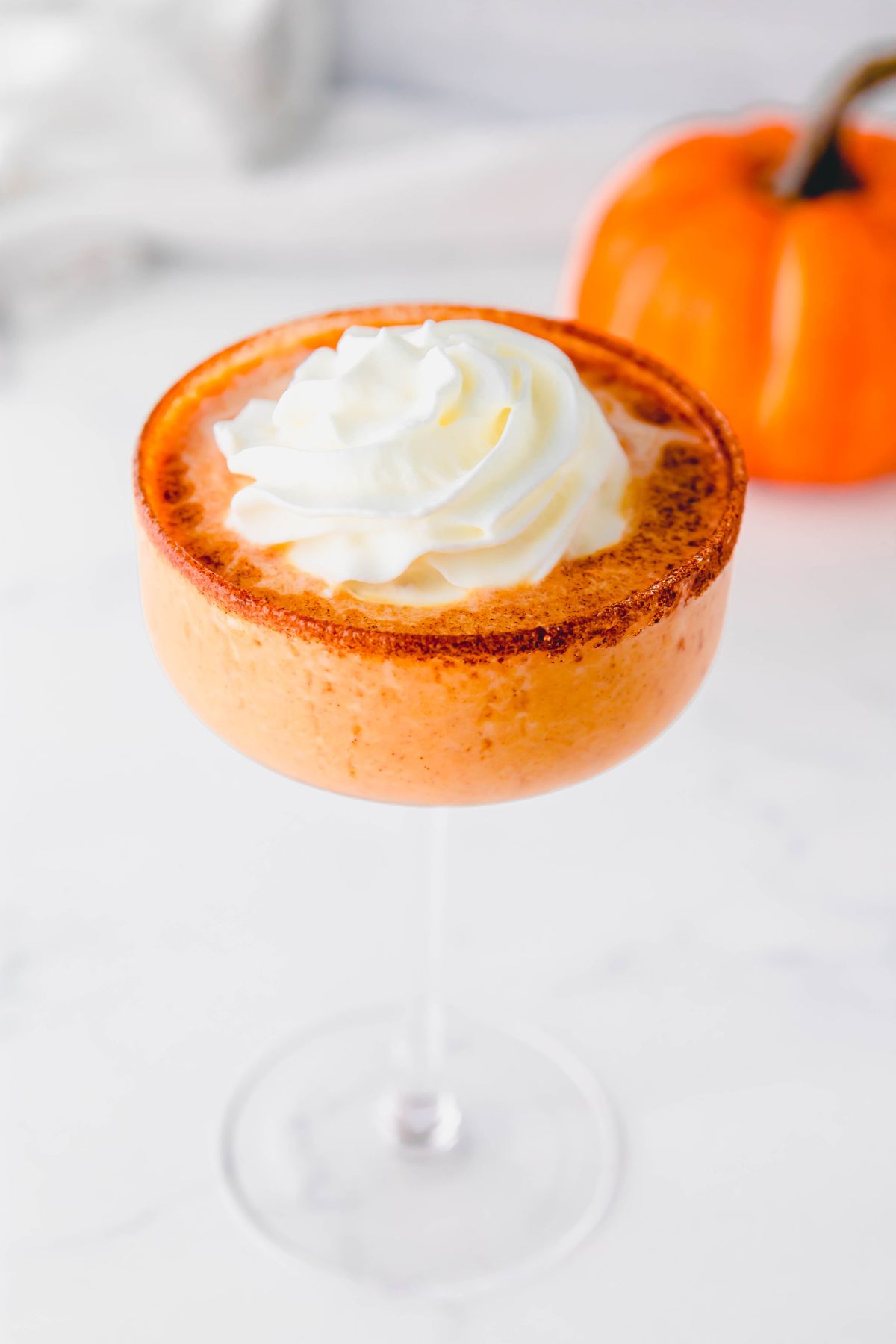 A pumpkin pie martini in a martini glass sitting on a white marble countertop