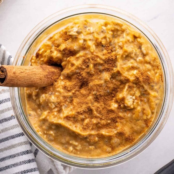 Pumpkin overnight oats in a clear glass jar on a white countertop