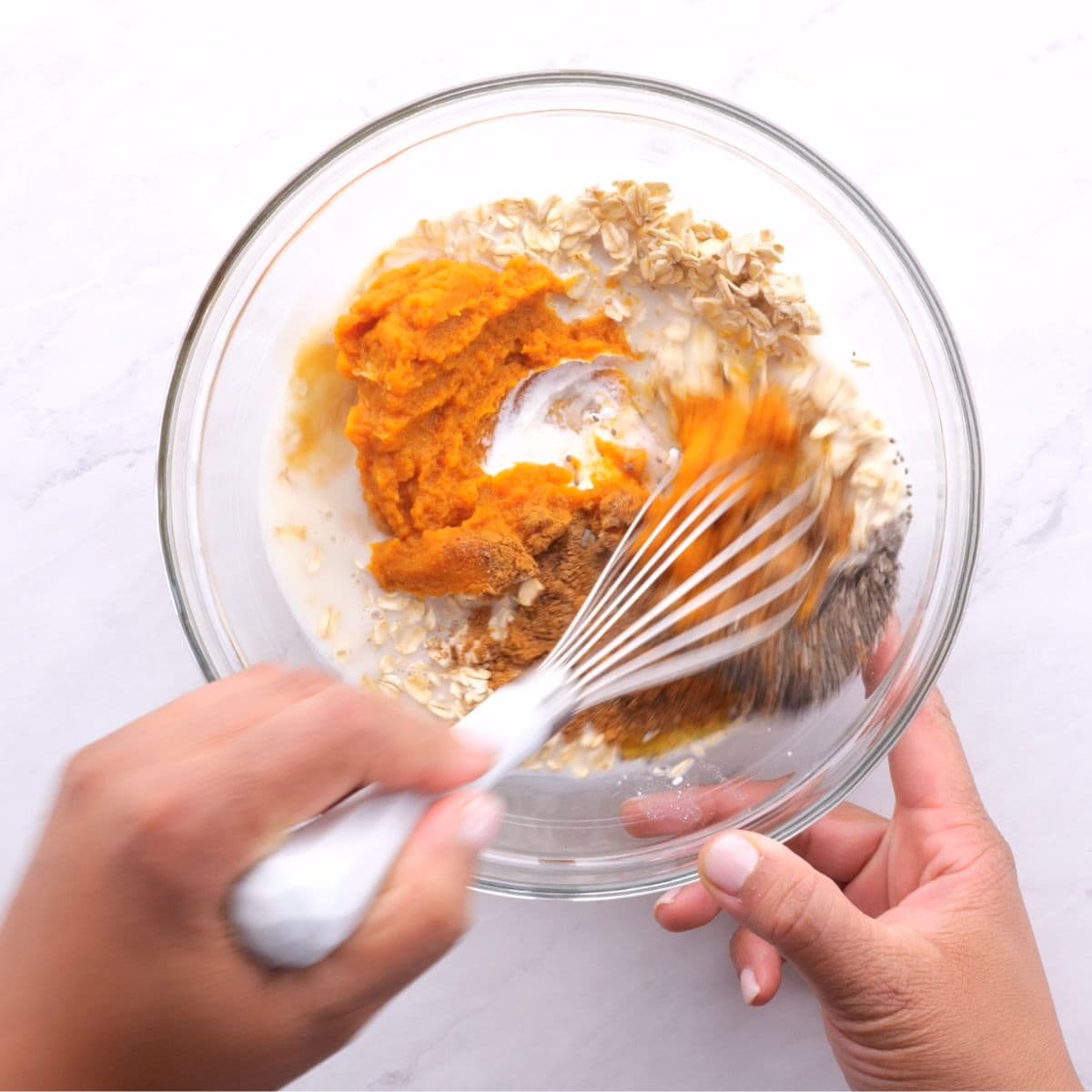 Stirring together overnight oats in a glass bowl with a whisk