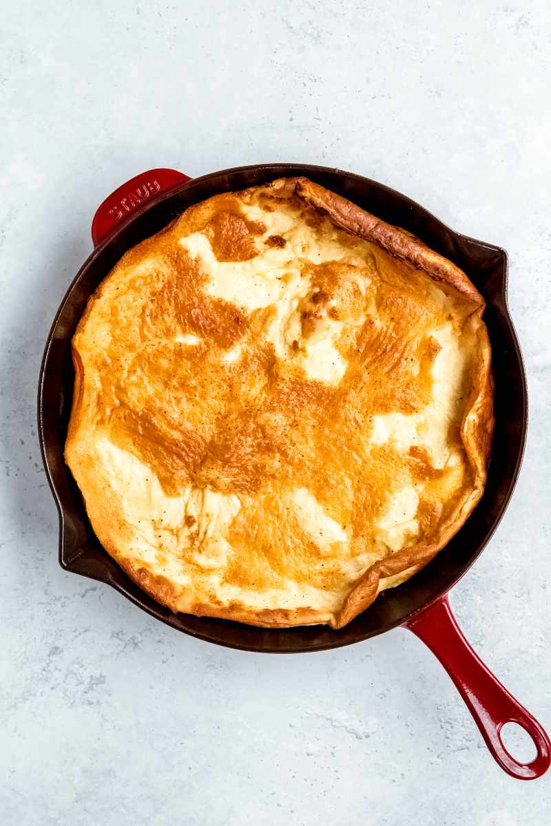 Overhead of a baked finnish oven pancake in an enameled cast iron skillet.