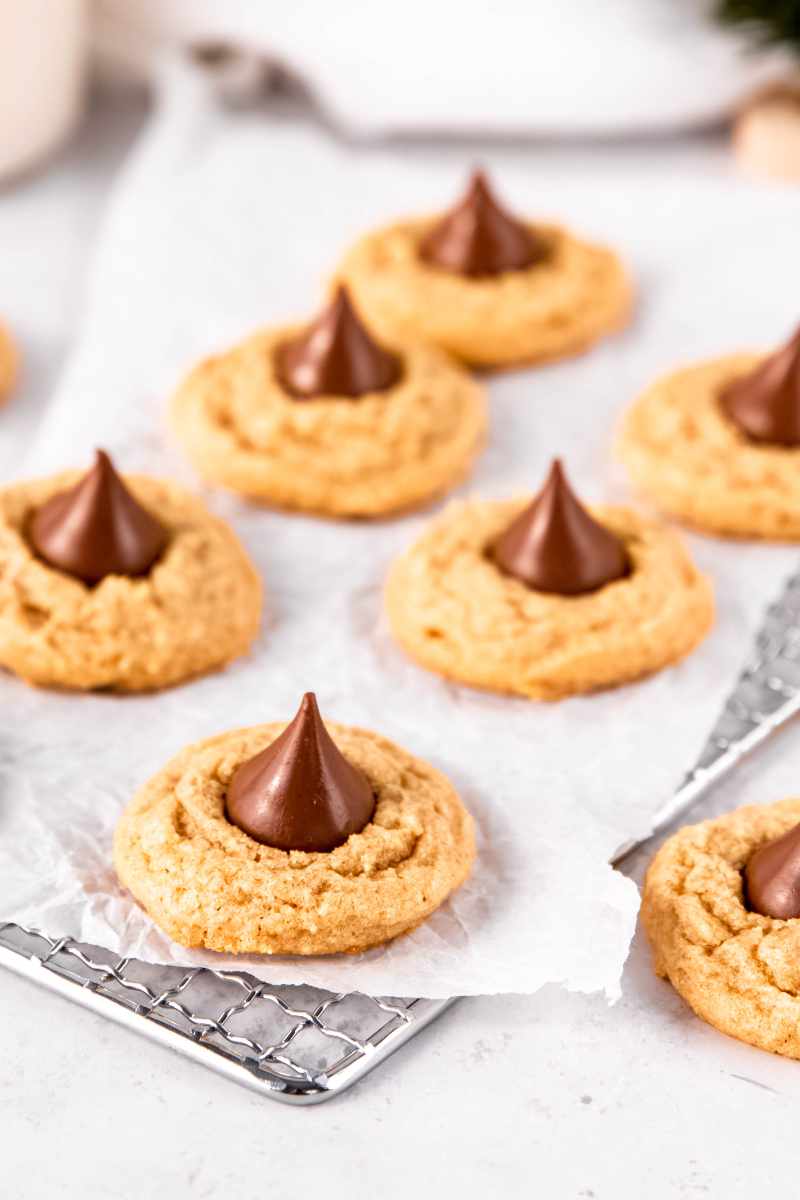 Peanut butter kiss cookies cooling on a parchment paper lined cooling rack.