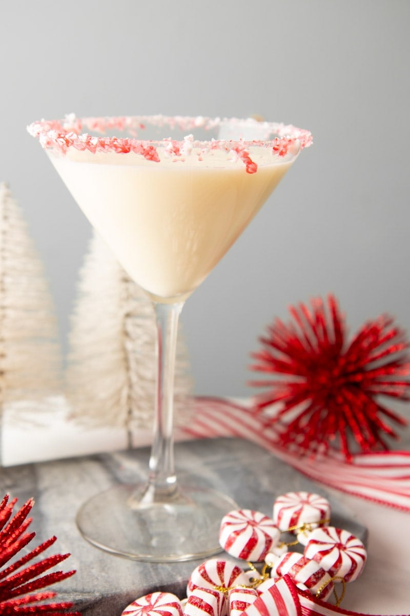 A Christmas candy martini stands with red and white candies at its base.