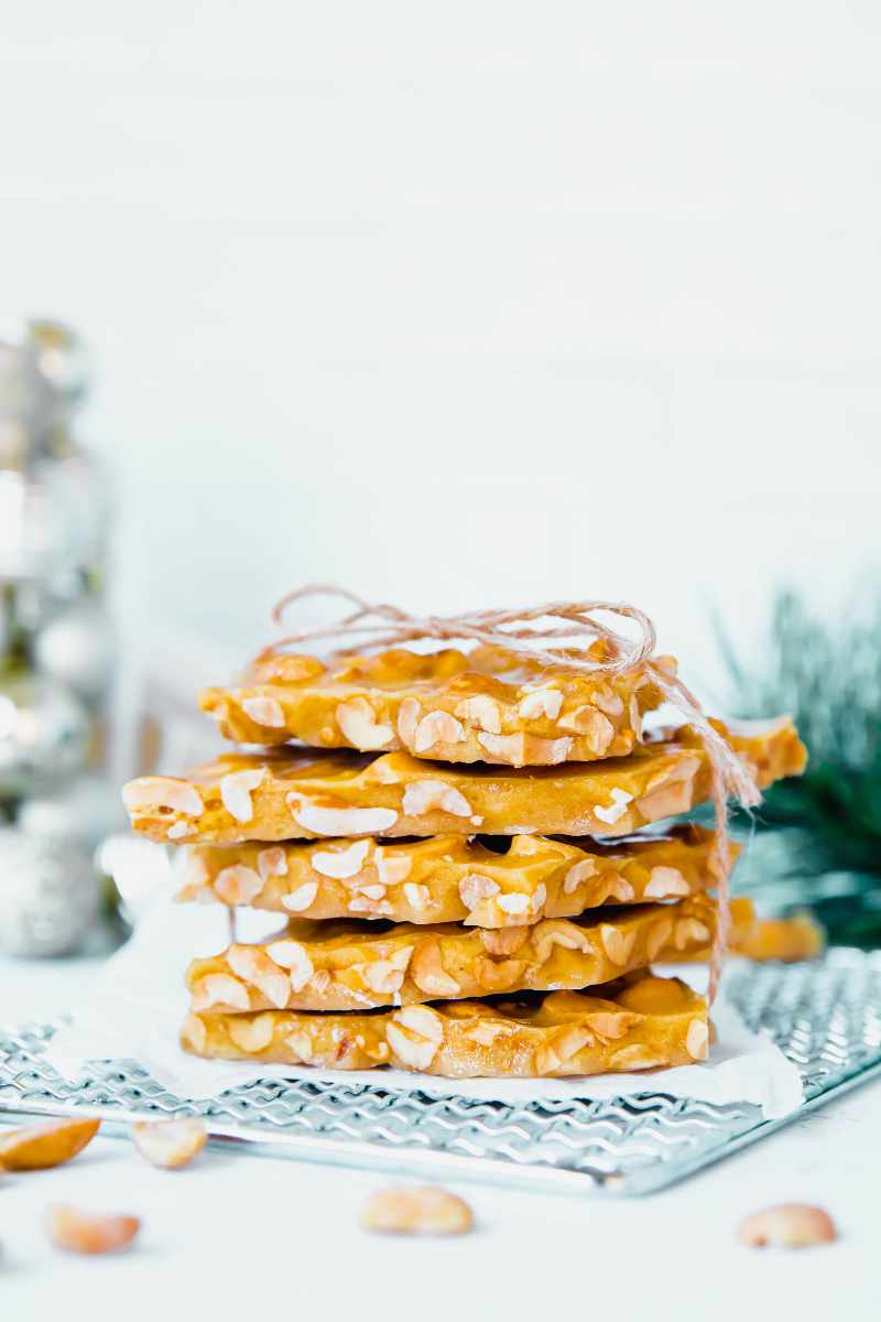 A stack of homemade peanut brittle wrapped in twine rests on a piece of parchment paper.