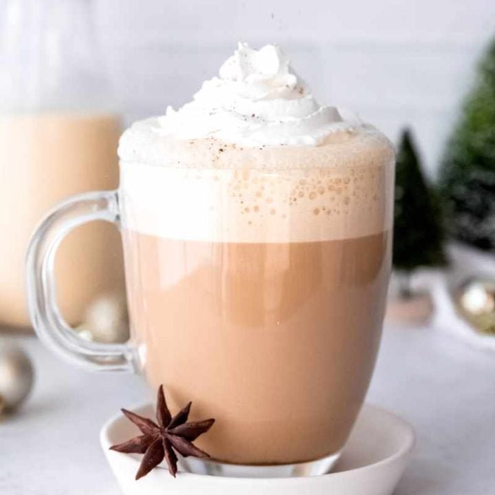 A sprinkling of nutmeg rains down over the whipped cream garnish on a festive holiday latte.