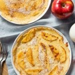 Two thin pancakes served on white plates with an apple and forks nearby.
