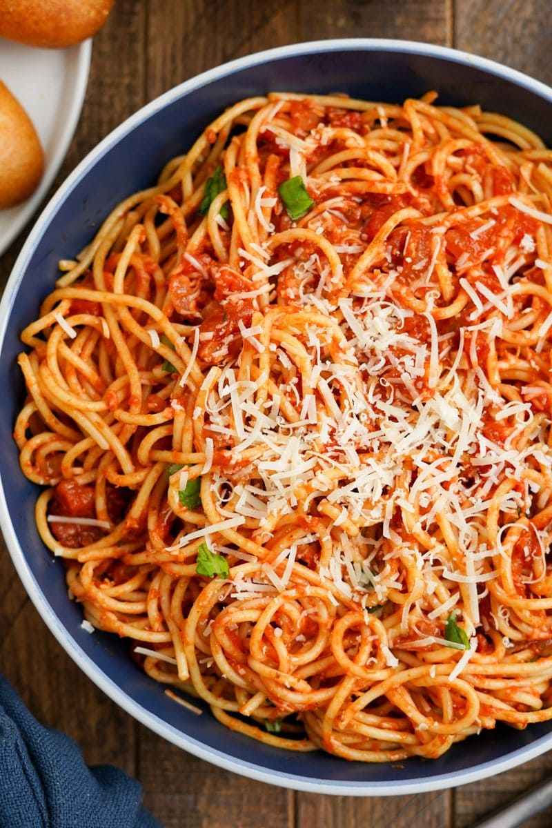 Tight view of a bowl of arrabbiata pasta topped with shredded parmesan cheese.