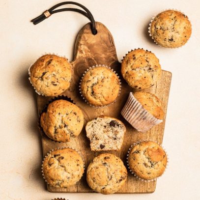 Overhead of gluten-free banana muffins on a wooden cutting serving board.