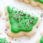 A Christmas tree sugar cookie decorated with green sugar cookie icing and sprinkles