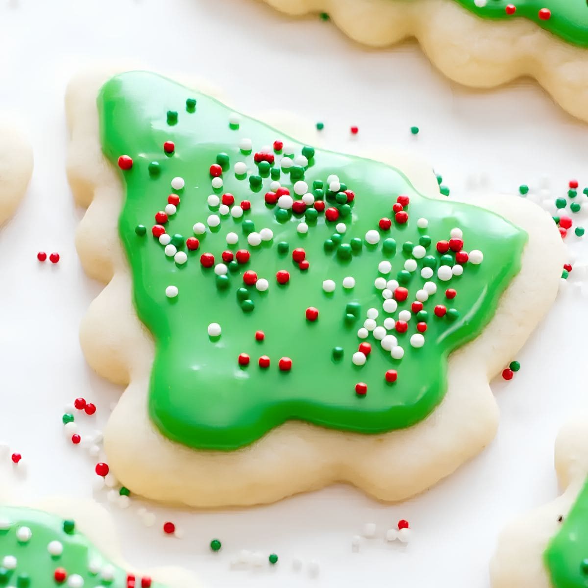 A Christmas tree sugar cookie decorated with green sugar cookie icing and sprinkles