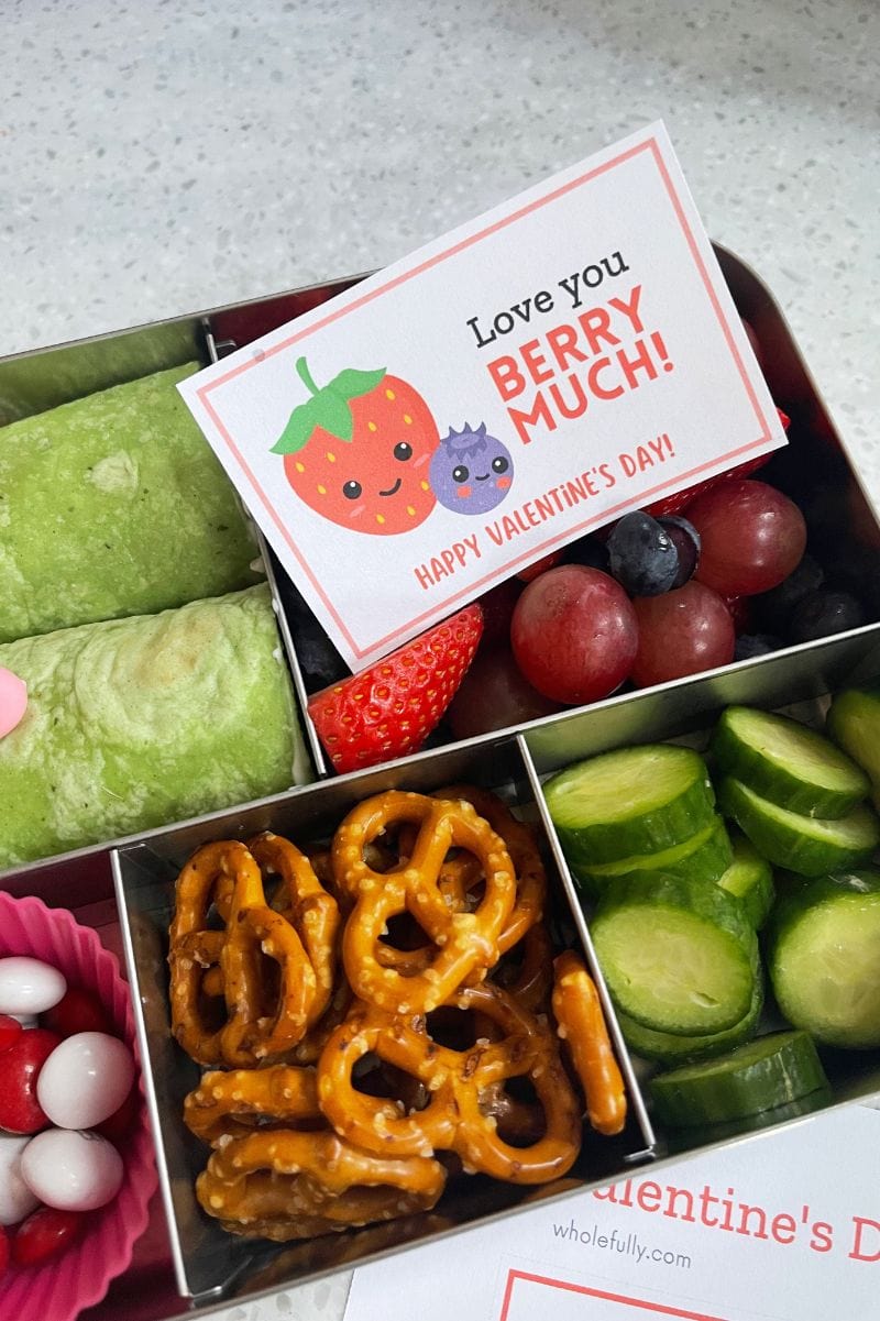 A cute valentine message for kids with smiling berries beside the words, "Love you berry much!" nestled into fresh berries packed in school lunch.