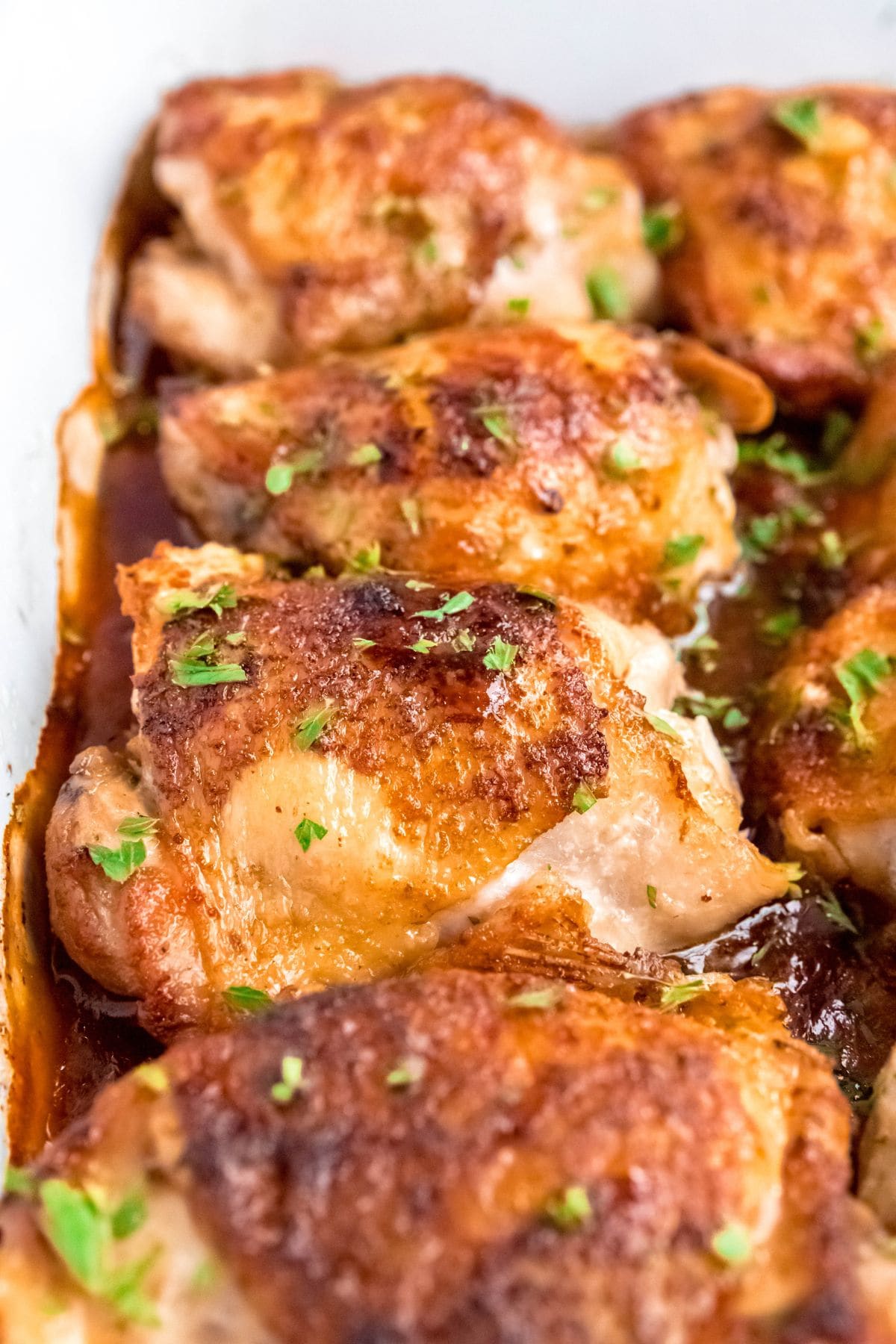 Close-up of honey glazed chicken thighs topped with fresh herbs