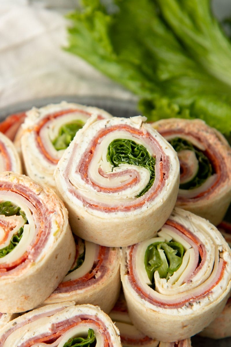 Italian sandwich wraps sliced into individual bites and stacked on a platter.