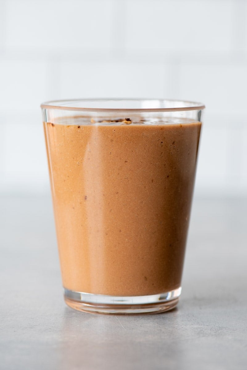 A creamy, nutty, mocha smoothie made without banana in a glass on a light background.