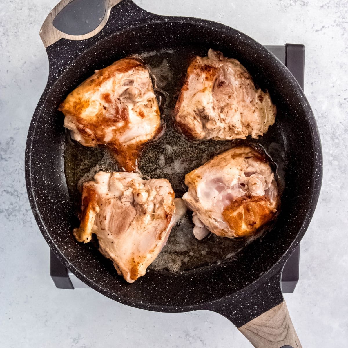 Seared chicken thighs browning in a skillet