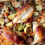 Close view of roasted chicken pieces and root veggies such as potatoes and carrots. A text overlay reads, "Sheet Pan Lemon Chicken."