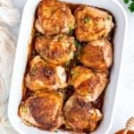 A baking dish of baked honey garlic chicken thighs, golden and glazed