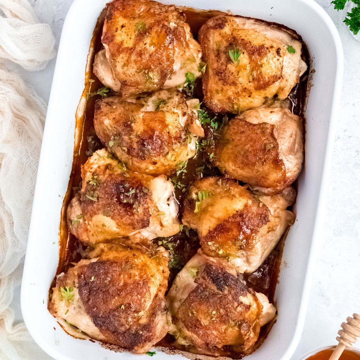 A baking dish of baked honey garlic chicken thighs, golden and glazed