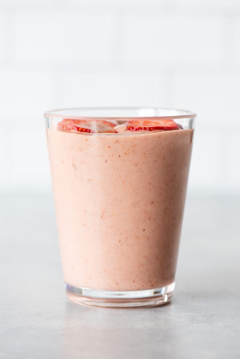 A light pink, strawberry smoothie made without banana in a glass on a light background.