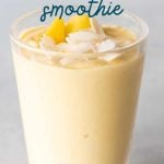 Top view of a mango smoothie topped with coconut flakes and mango pieces in a tall glass. A text overlay reads, "Banana-Free Mango Smoothie."