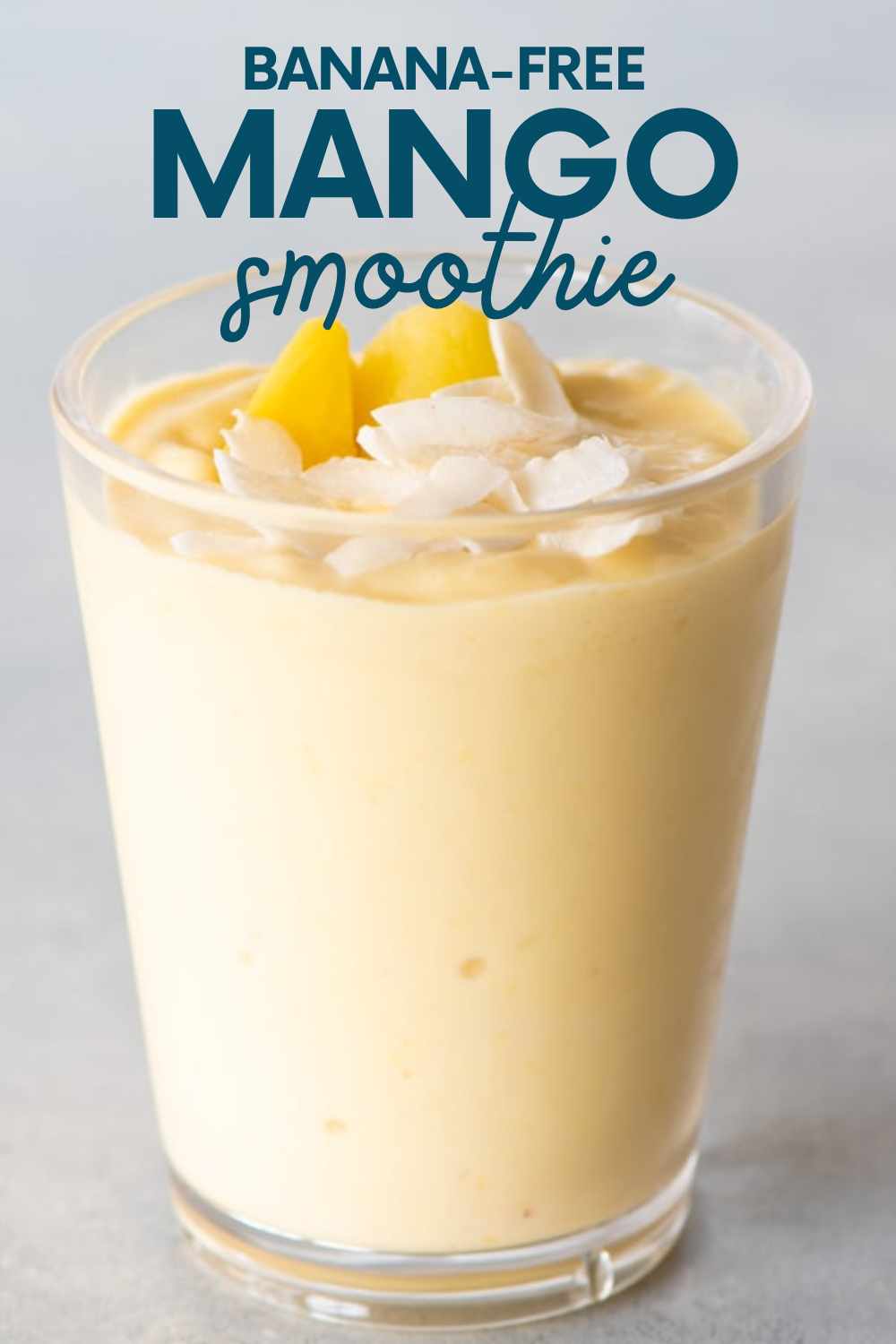 Top view of a mango smoothie topped with coconut flakes and mango pieces in a tall glass. A text overlay reads, "Banana-Free Mango Smoothie."