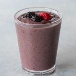 Top view of a mixed berry smoothie in a glass on a light background.