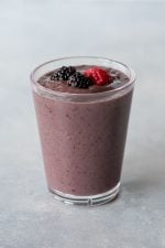 Top view of a mixed berry smoothie in a glass on a light background.
