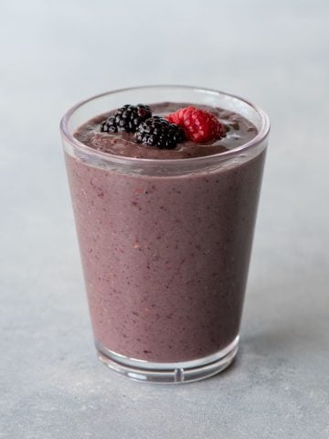 Top view of a mixed berry smoothie in a glass on a light background.