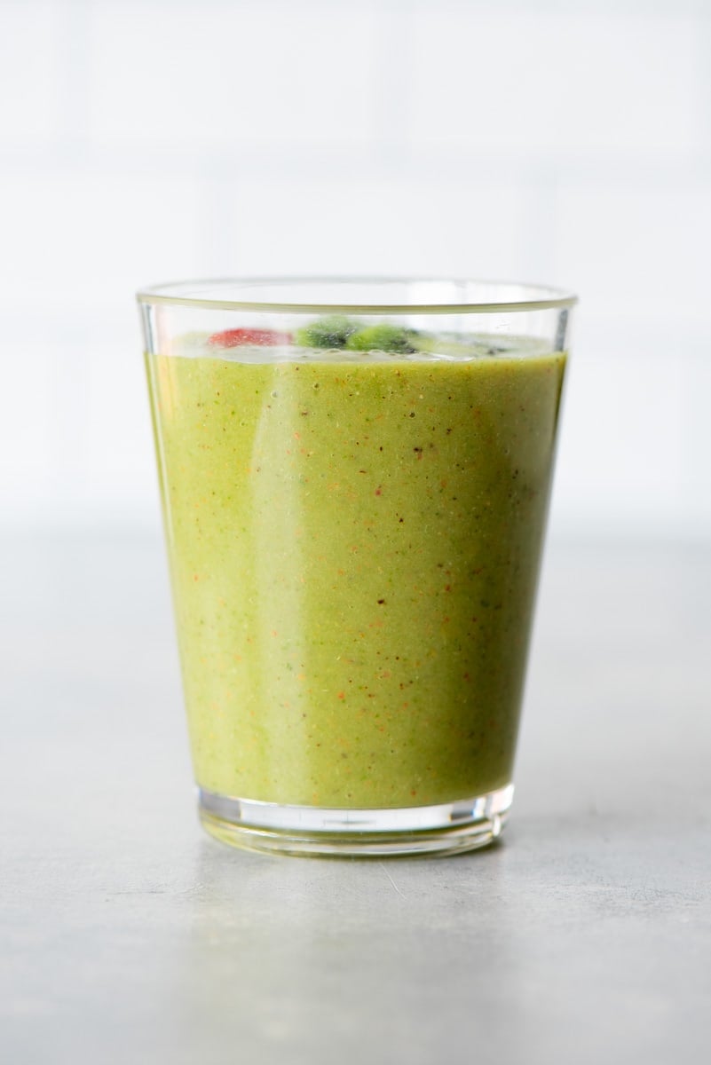 A blended frozen strawberry and kiwi drink in a tall glass on a light background.