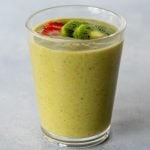 Top view of a strawberry kiwi smoothie in a glass topped with two thin slices of strawberry and kiwi.