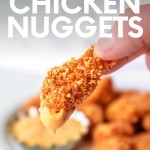 Two fingers hold up a crispy chicken nugget with creamy sauce on one end. A text overlay reads, "Homemade Chicken Nuggets."