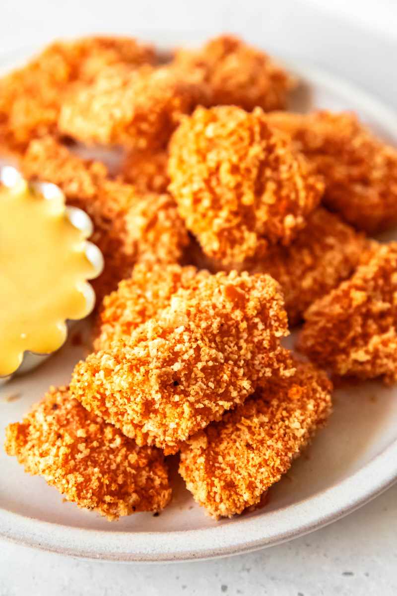 Homemade chicken nuggets on a white platter.