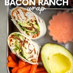 Two halves of a chicken wrap with spicy ranch dipping sauce packed in the large lunchbox compartment with carrot sticks and an avocado half. A text overlay reads, "Chicken Bacon Ranch Wrap."