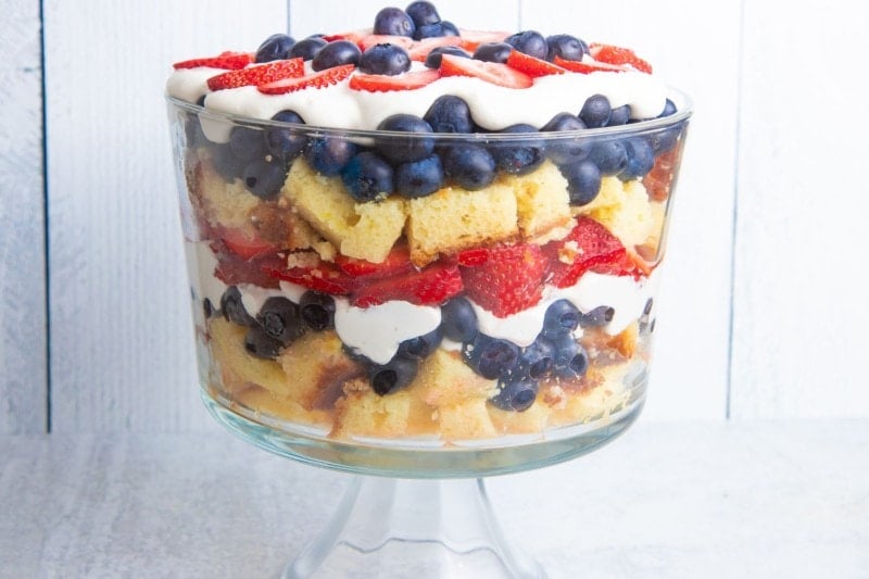 Closer view of a festive berry trifle in a trifle dish on a light background.