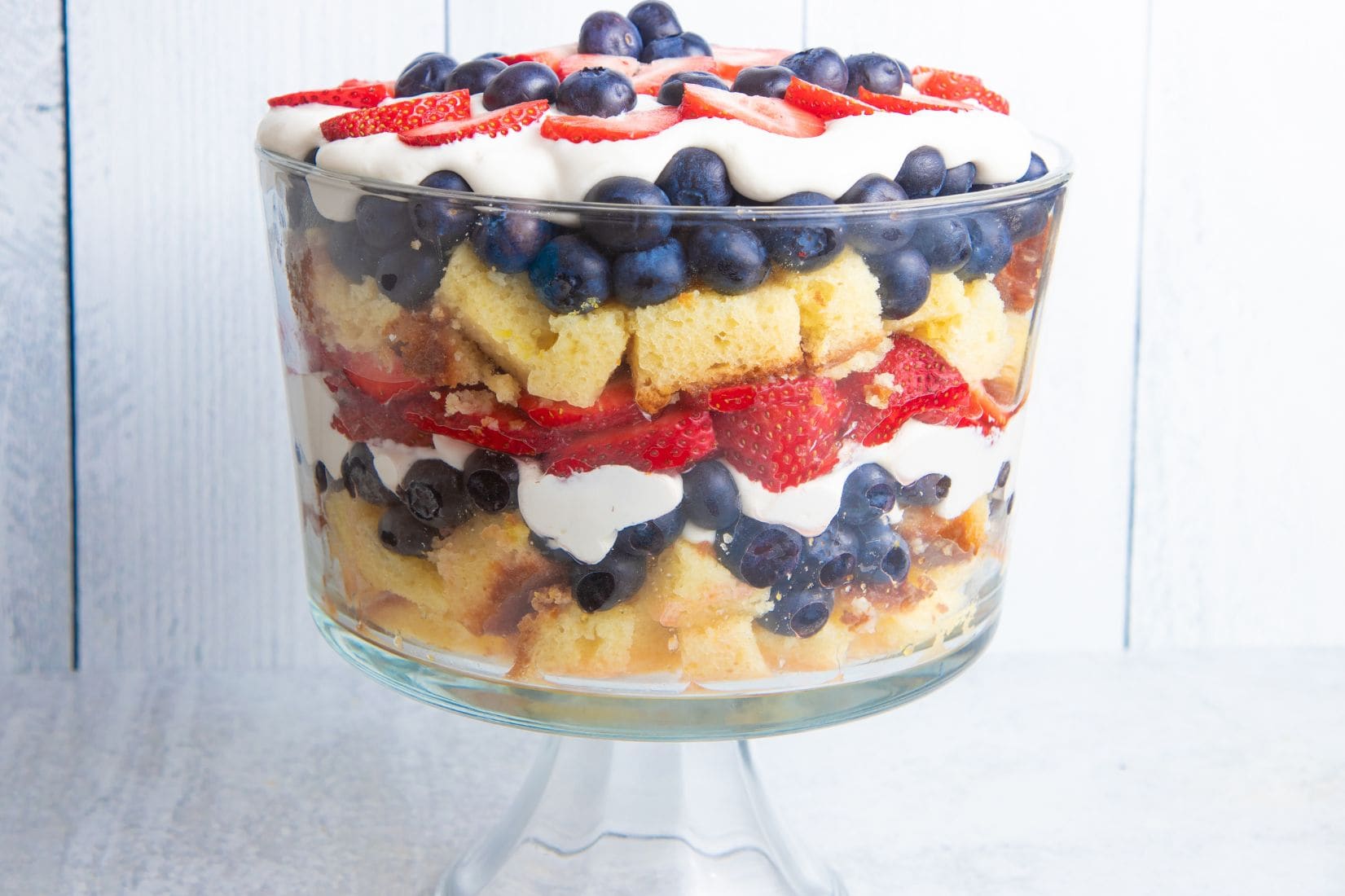 Closer view of a festive berry trifle in a trifle dish on a light background.