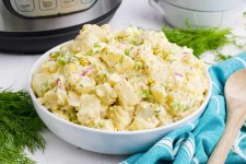 Close view of a white serving bowl piled high with creamy potato salad made in an instant pot.