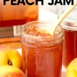 A small wooden spoon rests in an open pint jar of bourbon peach jam. A text overlay reads, "Bourbon Peach Jam."