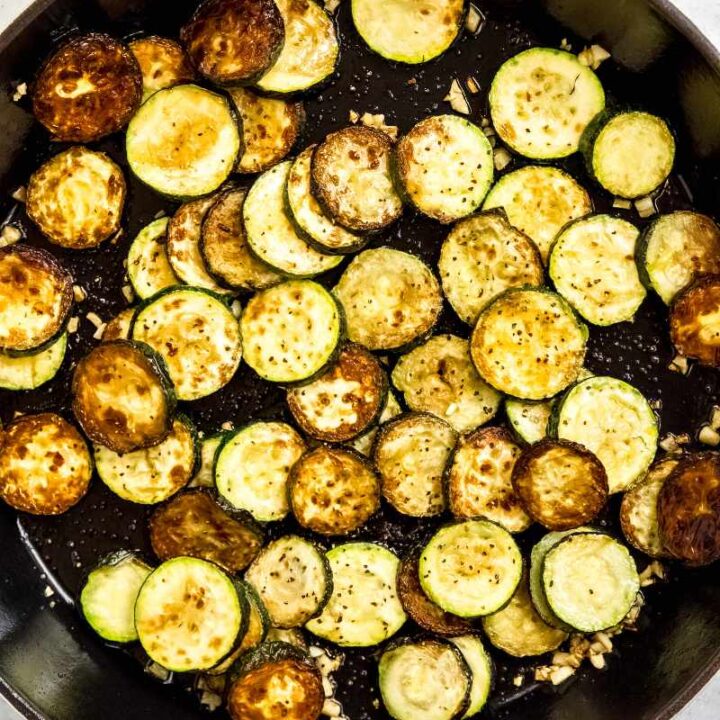 Top view of sauteed zucchini and garlic in an enameled cast iron skillet.