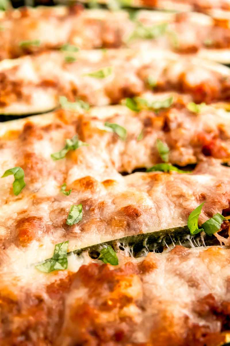 Close view of cheesy baked squash boats garnished with chopped fresh basil.