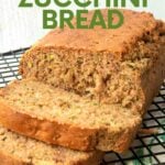 Close view of a loaf of gluten-free zucchini bread on a cooling rack with two slices cut showing the tender inside. A text overlay reads, "Gluten-Free Zucchini Bread."