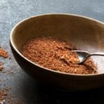 A spoon rests in a wooden bowl with homemade taco seasoning in it.